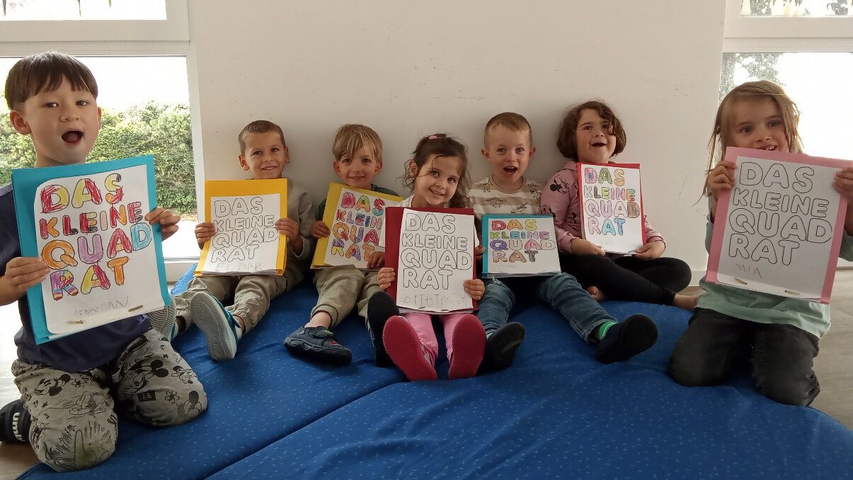 Die Kinder der Kita Pfuhlstrasse zeigen glücklich ihre selbstgestalteten Faltbücher "das kleine Quadrat".
